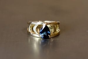 18ct yellow gold and blue Australian pear sapphire engagement ring with moon shapes. Men's brushed titanium wedding band.