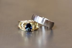 18ct yellow gold and blue Australian pear sapphire engagement ring with moon shapes. Men's brushed titanium wedding band.